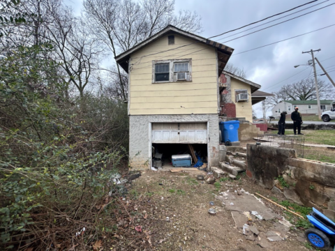 Back view of a occupied house in poor condition, highlighting significant deterioration and the need for extensive repairs.