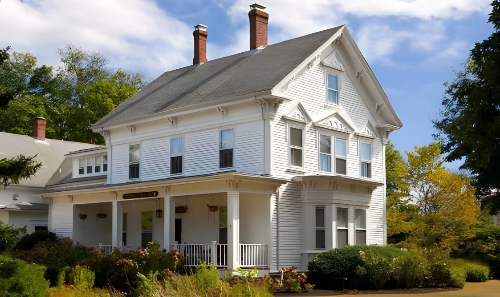 Victorian-style house in Attleborough, MA with white siding and lush landscaping.