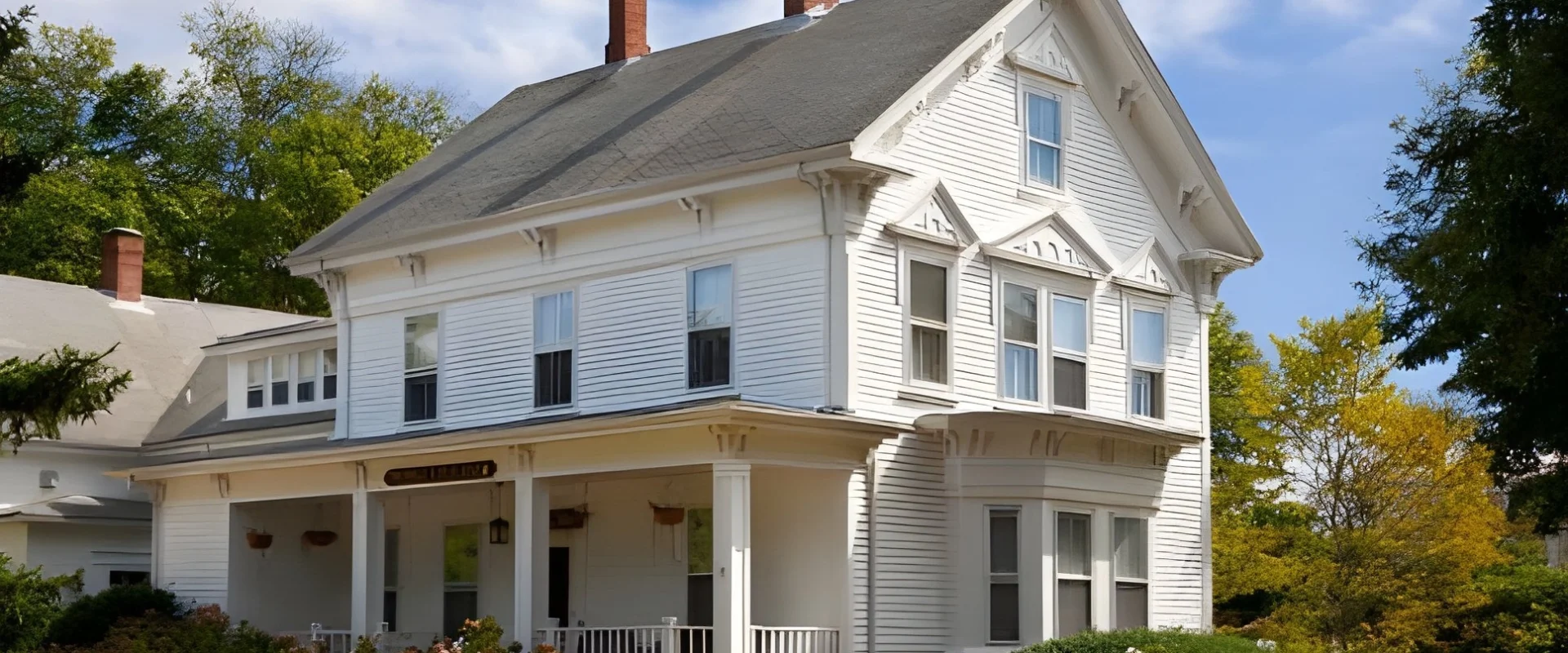 Victorian-style house in Attleborough, MA with white siding and lush landscaping.