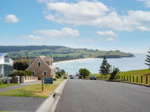 Seaside view of a coastal road with homes and a beach in the distance.