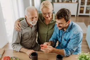 Family enjoying time together, looking at a smartphone at a dining table.
