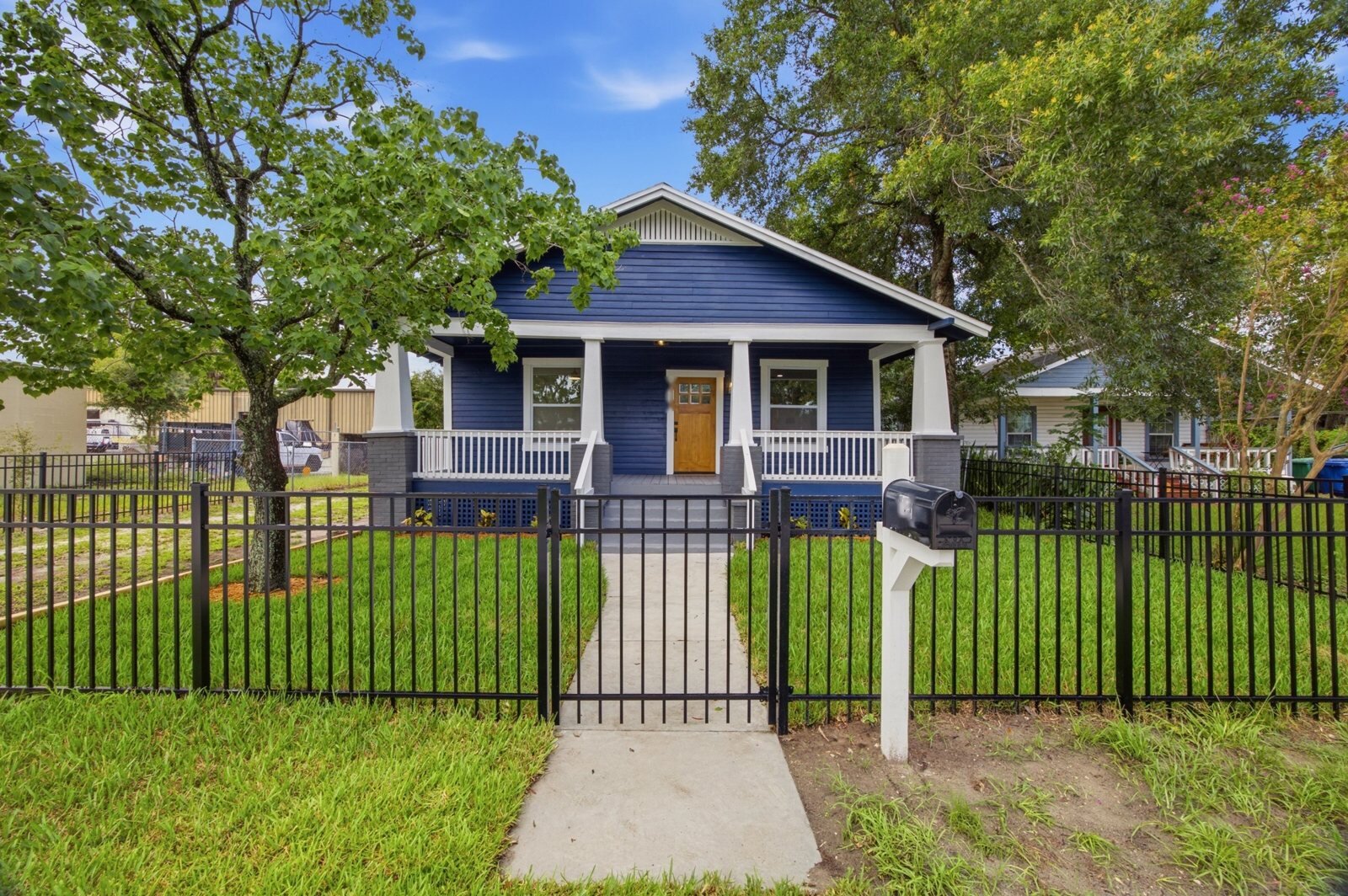 Tampa bungalow after renovation: navy siding, new porch, new fence and fresh lawn