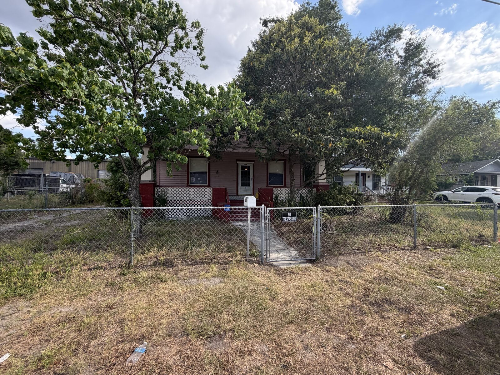 Tampa bungalow before: overgrown yard, chain-link fence and worn exterior, bought as-is for cash