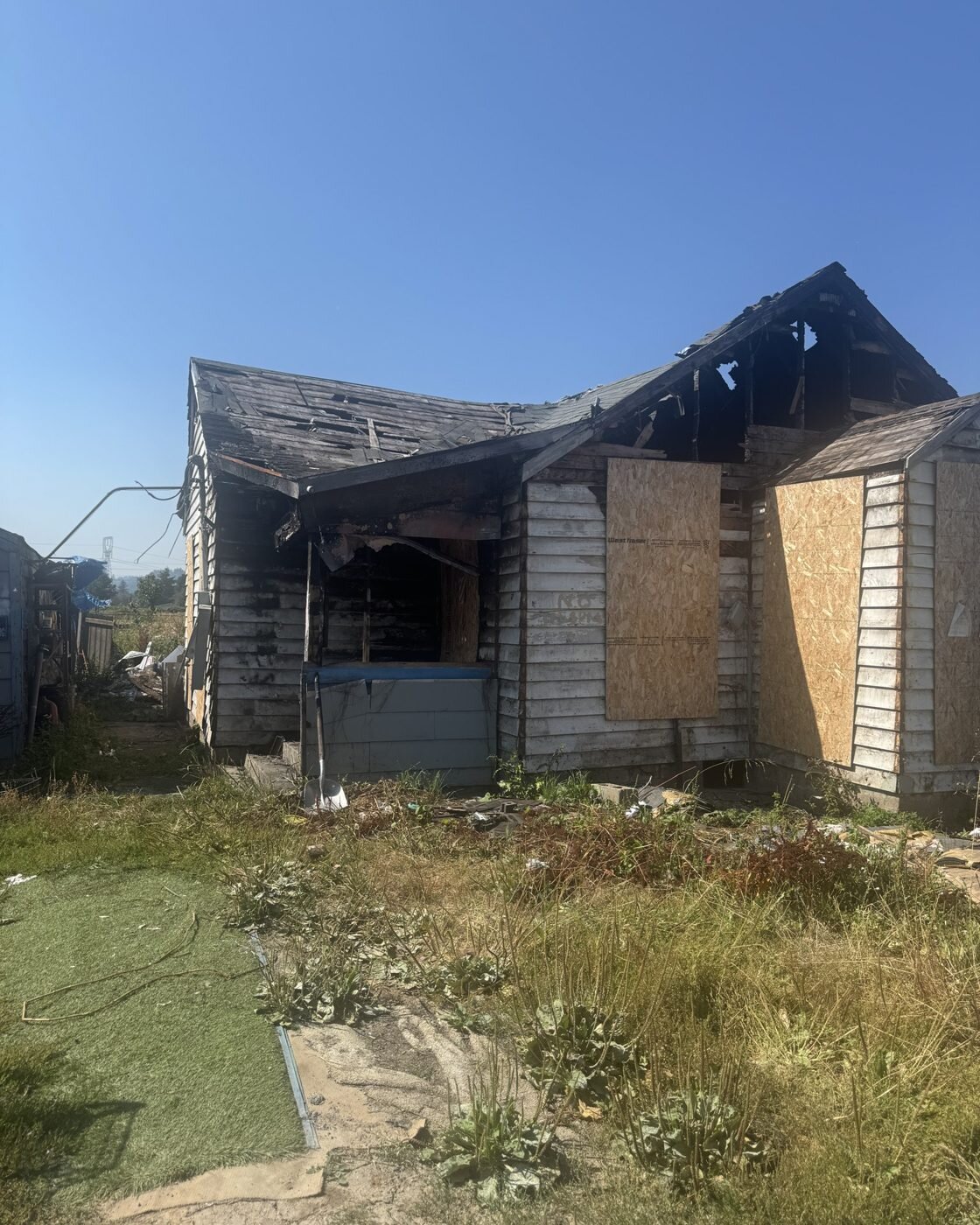 Fire-damaged house on 46th Ave in Longview, WA with boarded windows