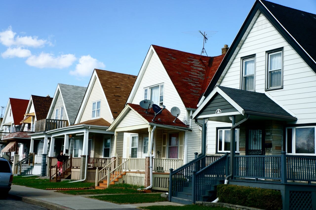Row of charming suburban homes with distinctive peaked roofs and front porches, illustrating diverse residential real estate options in a neighborhood setting.