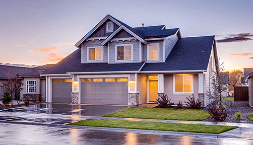 Modern two-story home with illuminated windows and a well-manicured lawn, highlighted in a twilight setting, representing an ideal residential real estate listing.
