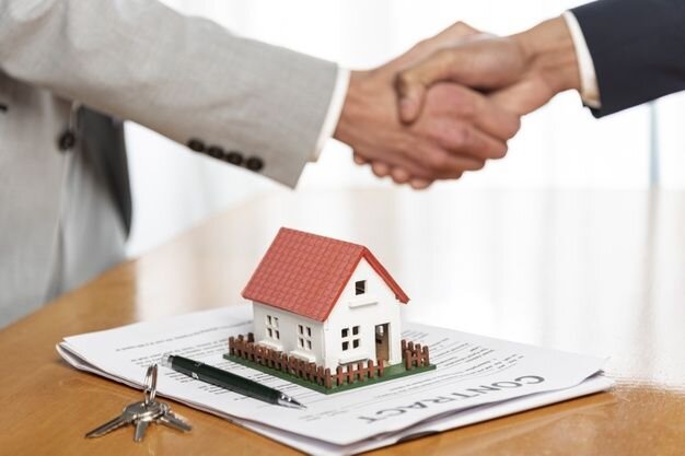  A handshake between two business professionals over a contract on the desk, with a model house and keys in the foreground, symbolizing a real estate agreement.