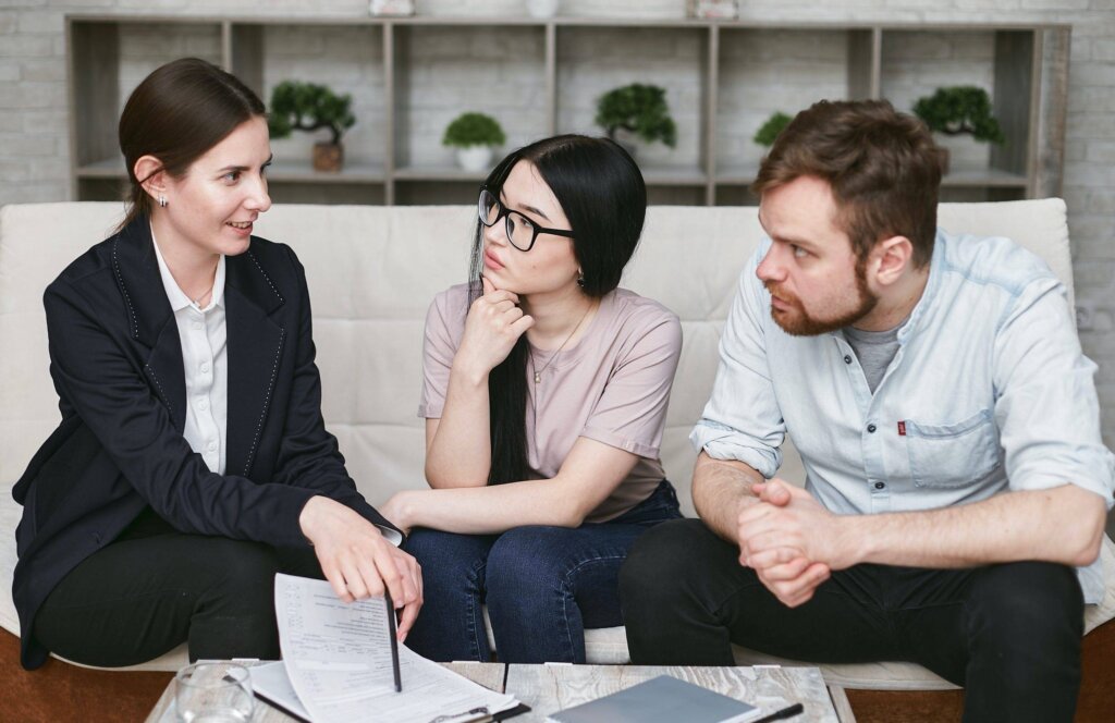 Couple listening to a professional woman explaining documents during a meeting.