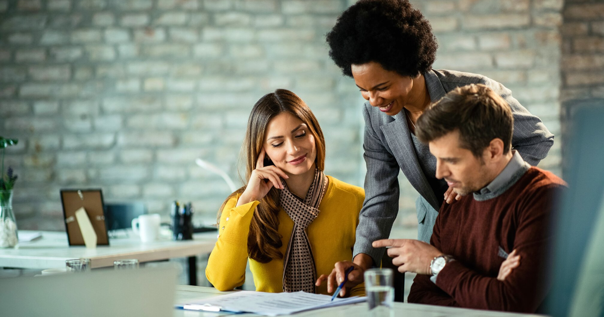 Professional real estate agent consulting with a couple in an office setting, reviewing documents and discussing potential property deals with a focus on customer satisfaction.