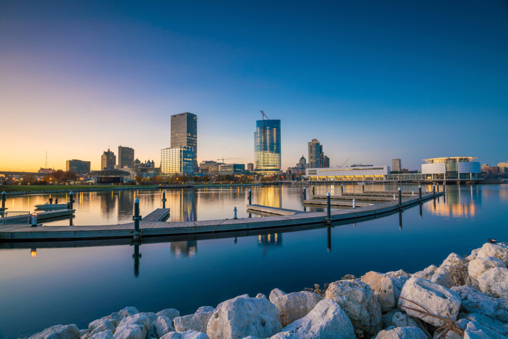 A beautiful city skyline captured during sunset, with the waterfront reflecting the city lights and the skyline illuminated against the evening sky.