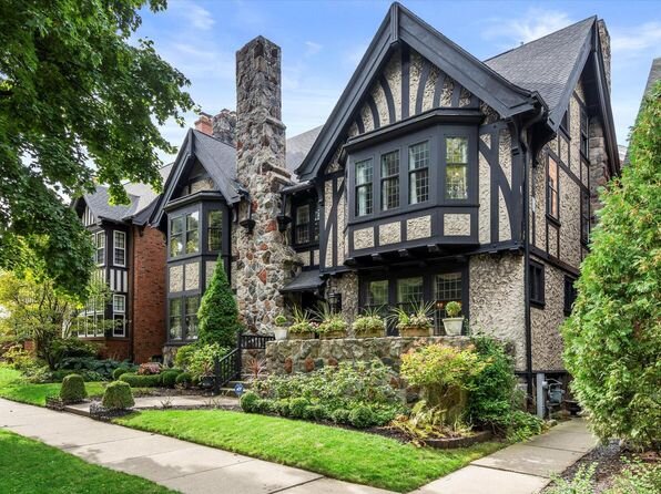  A beautiful Tudor-style home featuring distinctive black timber framing, stone chimney, and well-manicured landscaping. The home exudes classic charm and historic character, situated in a tree-lined neighborhood.