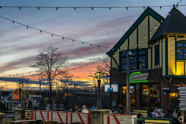 Charming restaurant patio at sunset, adorned with string lights and vibrant signage, creating a cozy atmosphere as people enjoy their evening dining experience.