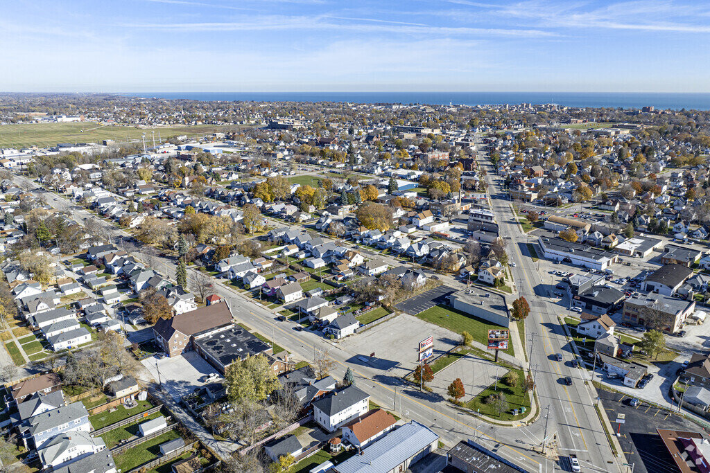 An aerial view of a residential neighborhood, showcasing a vast spread of houses and streets. The image captures a broad perspective of the area, illustrating the layout and structure of a suburban community with a view extending to the horizon.