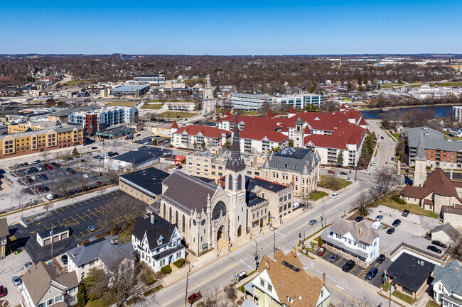 Aerial photograph of a downtown area featuring a mix of historic and modern buildings, with a prominent church and other community structures.