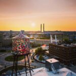 Stained-glass water tower with sunset city skyline.