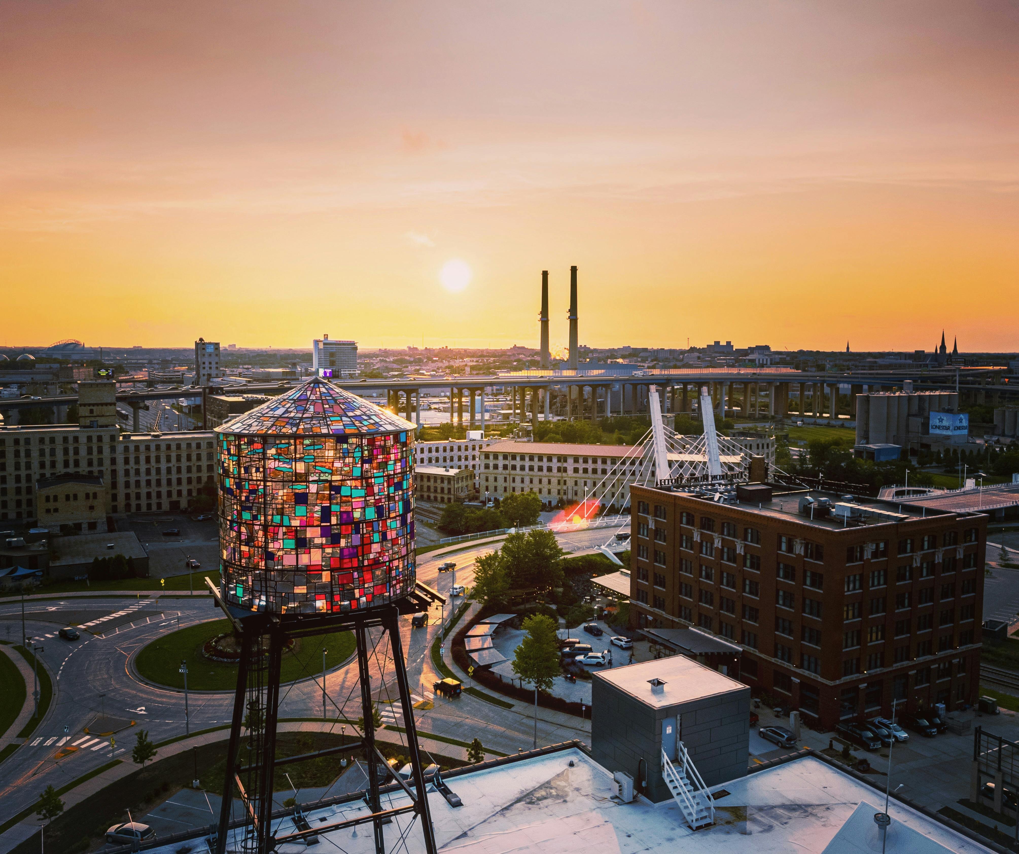 Stained-glass water tower with sunset city skyline.