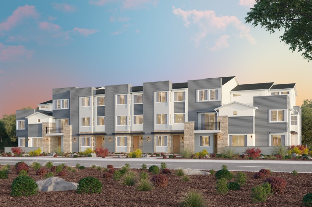 Modern three-story townhouse complex with landscaped surroundings at sunset.