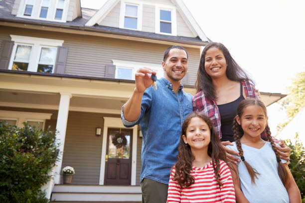 Happy family standing in front of their new home, holding house keys and smiling.