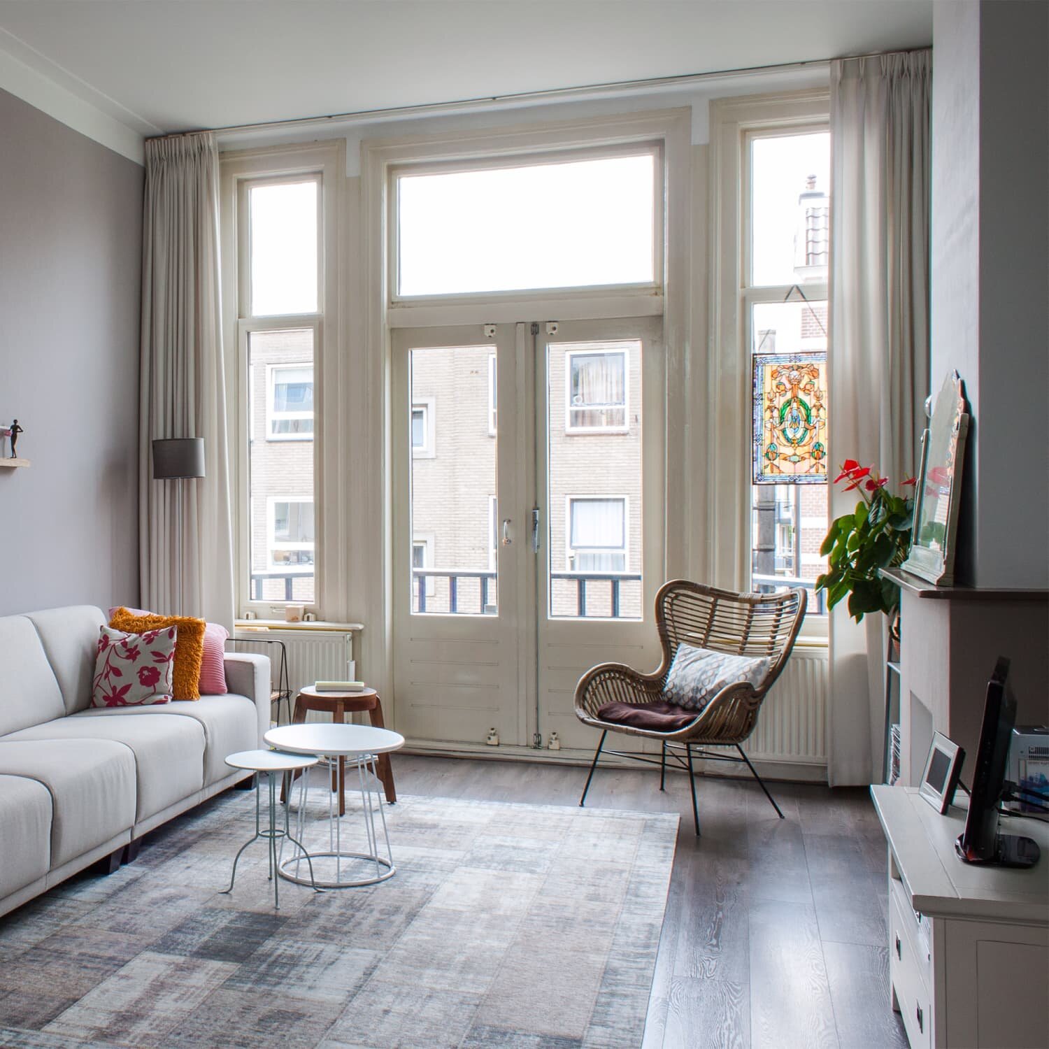 Bright and clean living room with modern decor, natural light from large windows, and cozy furnishings.