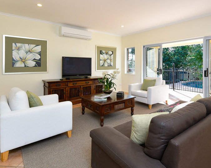A bright, neatly staged living room with modern furniture, decorative accents, and an open view to a patio area.