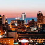 Milwaukee city skyline at dusk, with buildings lit up and a view of the horizon.