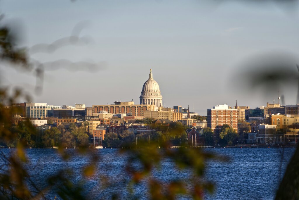 View of downtown Madison, with the State Capitol building in the background and the lake in the foreground.