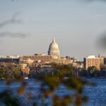 View of downtown Madison, with the State Capitol building in the background and the lake in the foreground.