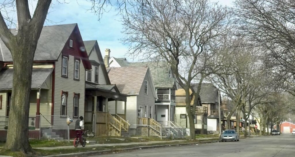 A residential street in Milwaukee with row houses and a child riding a bike.