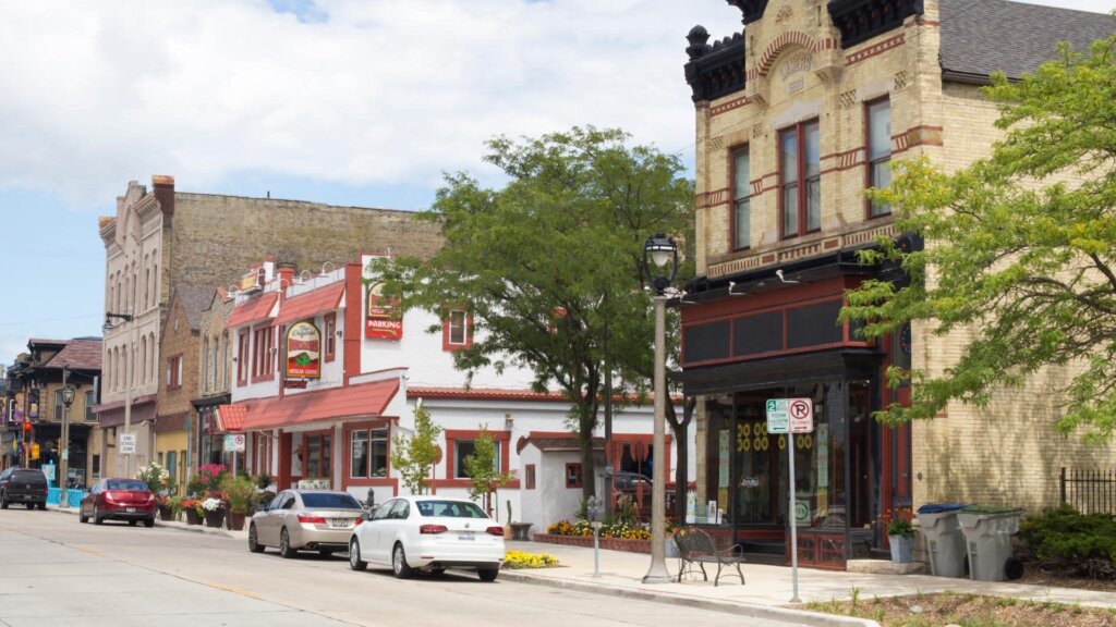 A vibrant street view in Milwaukee with restaurants, shops, and trees lining the sidewalk
