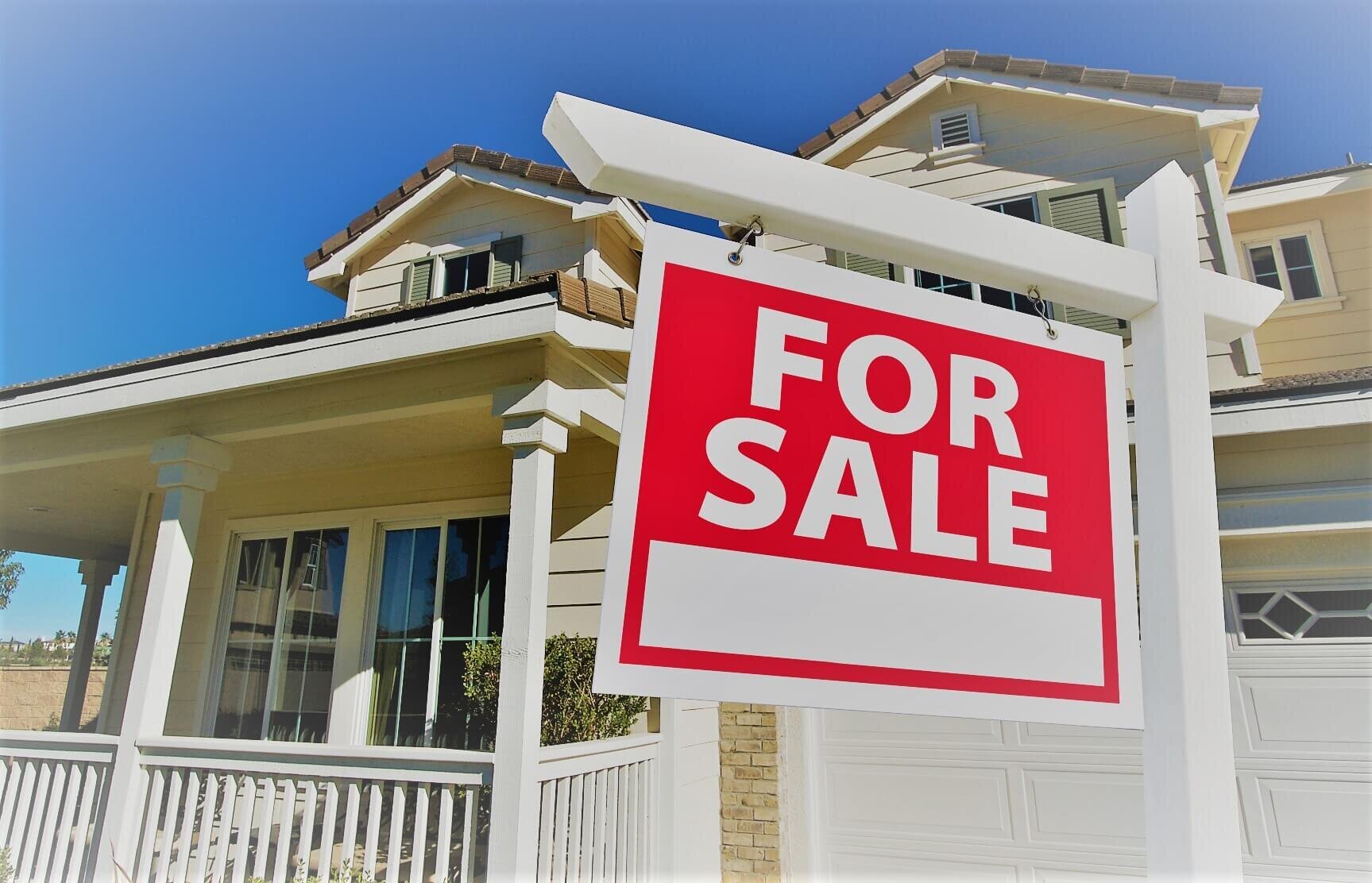 "House with a 'For Sale' sign in front of a suburban home.