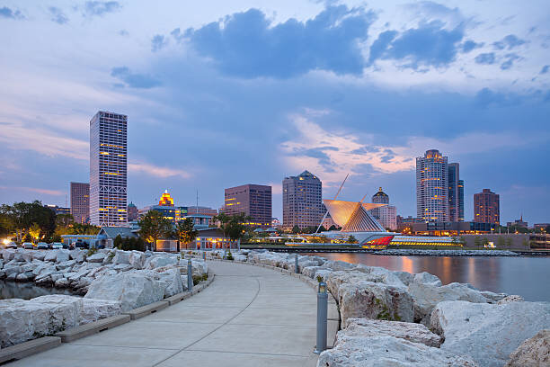Downtown Milwaukee skyline at dusk with a waterfront path, including the Milwaukee Art Museum, representing the vibrant city.