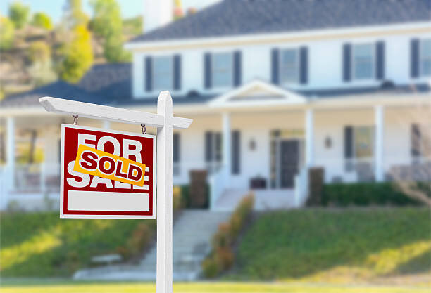 A "For Sale" sign with "SOLD" stamped across it in front of a house, symbolizing a successful property sale.