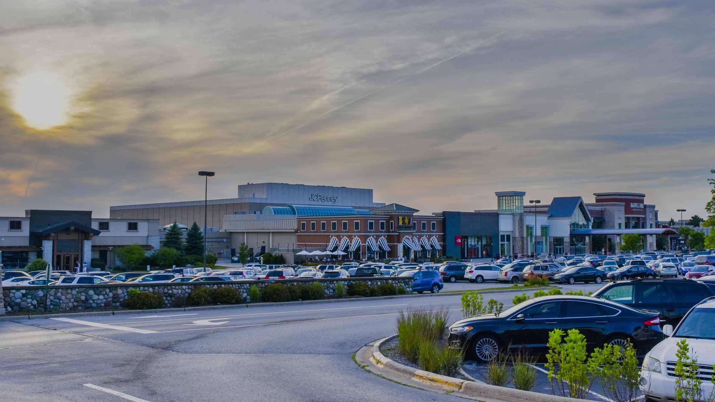Busy shopping center in Brookfield with a JC Penney store and a crowded parking lot at sunset.
