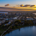 Aerial view of downtown Madison, Wisconsin, at sunset, with the state capitol and surrounding landscape.