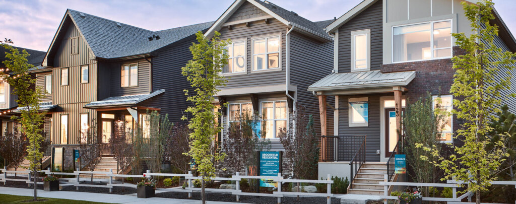 Newly built homes in a modern Brookfield residential neighborhood with trees, fences, and signs outside each house.