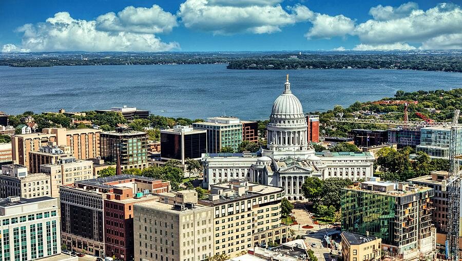 Aerial view of downtown Madison, Wisconsin, with the state capitol building and Lake Monona in the background.