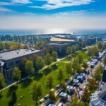 Aerial view of a lively outdoor market at HarborPark in Kenosha, with green lawns, tree-lined paths, and Lake Michigan in the background.