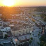 Aerial view of downtown Wauwatosa, Wisconsin at sunset, showing historic buildings, a train line, and surrounding trees.