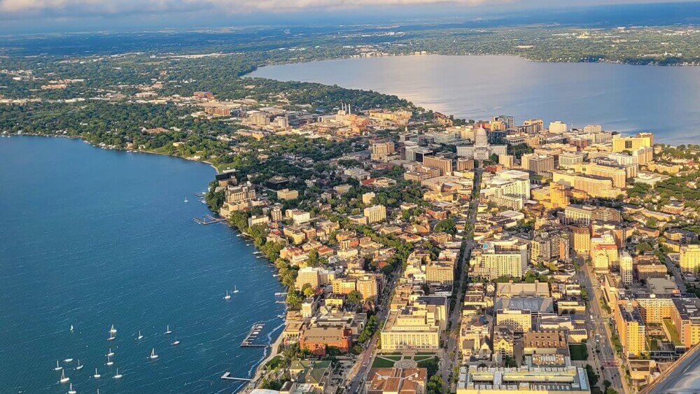 Aerial view of downtown Madison, Wisconsin, with the State Capitol and surrounding lakes, representing the local market for selling a house with water damage in Madison.