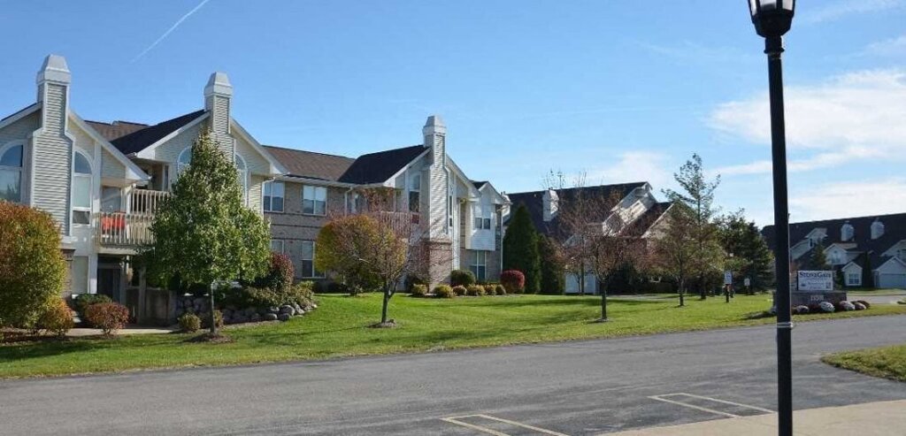 Modern suburban apartment buildings with manicured lawns and trees on a sunny day in New Berlin.