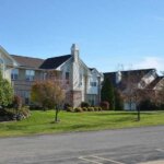 Modern suburban apartment buildings with manicured lawns and trees on a sunny day in New Berlin.