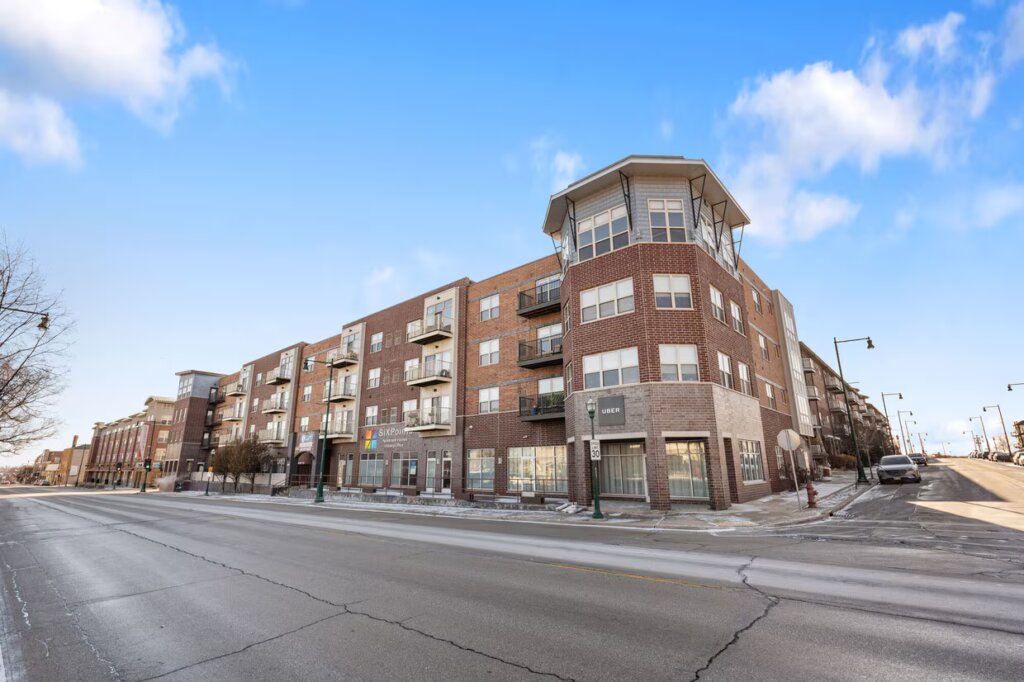 Primary exterior view of Six Points Apartments in West Allis, WI, showcasing a modern multi-story residential building with clean architectural lines.