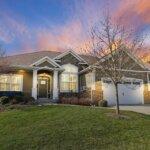 Luxury home at sunset with warm exterior lighting and vibrant sky.