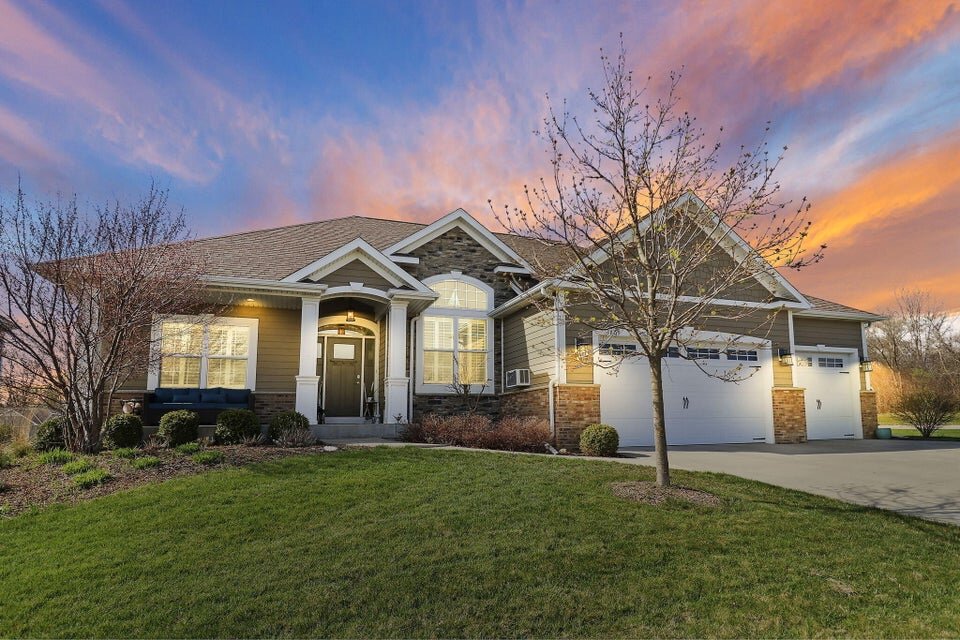 Luxury home at sunset with warm exterior lighting and vibrant sky.