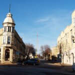 Historic downtown Wauwatosa, Wisconsin featuring vintage architecture, a turreted corner building, and a clock tower under a clear blue sky.
