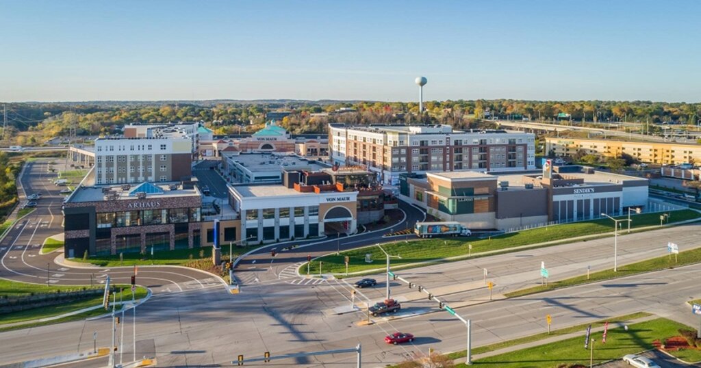 Aerial view of The Corners of Brookfield shopping and residential complex, featuring retail stores, apartments, and nearby highways under a clear blue sky.