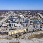 Aerial view of a commercial and residential area in Brookfield, Wisconsin, showing shopping centers, apartment buildings, and major highways.