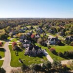 Aerial view of a suburban Brookfield neighborhood in autumn, featuring large single-family homes, colorful trees, and winding streets.