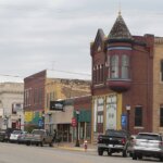 Historic downtown street in Ellsworth, Kansas, featuring early 20th-century brick buildings, local businesses, and parked vehicles along the main road.