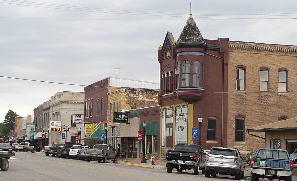 Historic downtown street in Ellsworth, Kansas, featuring early 20th-century brick buildings, local businesses, and parked vehicles along the main road.